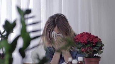tıbbi ilaçlar hapşırma ile masada oturan hasta genç kadın hapşırır ve mevsimsel alerjiler nedeniyle mendil burnunu darbeler