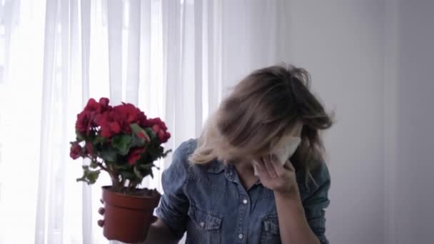Патоген, молодая девушка с цветами в руках страдает от аллергии на пыльцу постоянно чихает и салфетки с платком — стоковое видео