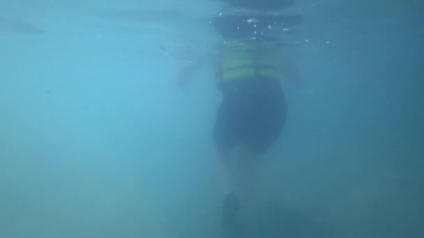 Активные выходные, турист, который отстает от экскурсионной группы в защитной одежде во время летних каникул идет вдоль опасного морского дна в водной пещере среди огромных камней, подводные съемки — стоковое видео