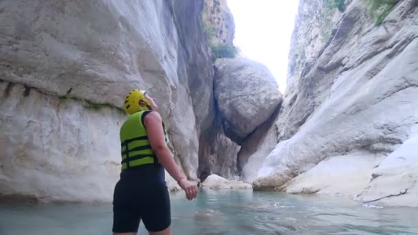 Extrem turism, lycklig aktiv turist flicka i skyddshjälm och kläder med nöje utforska vackra området i grottan med vatten på bakgrunden av stora stenar välja sport Weekend — Stockvideo