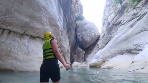 Turismo extremo, feliz chica turística activa en casco protector y ropa con placer explorar hermosa zona en cueva con agua en el fondo de enormes piedras elegir fin de semana deportivo — Vídeos de Stock