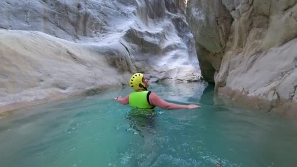 極端な旅行、極端な条件で女性のアクティブなライフスタイルの休日は、巨大な石の間に防護服で泳いでいます — ストック動画