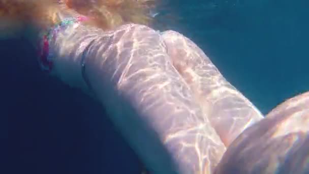 Swimming tourist, young slim girl with beautiful booty diving loving active lifestyle on sea weekend swims vigorously into water on beautiful sunny day, underwater video back view — Stock Video