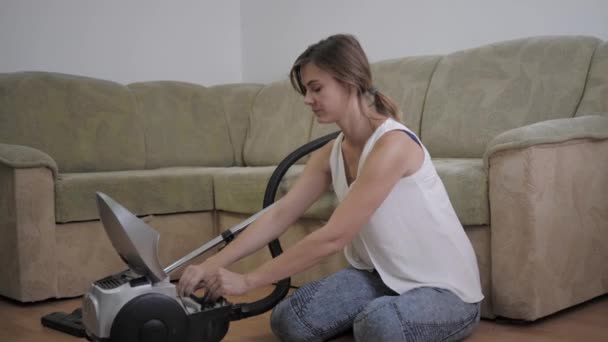 Toza alerjisi olan genç kadın temizlik ten sonra odada yerde oturan elektrikli süpürgeden gelen kirli poşet nedeniyle sürekli hapşırır — Stok video