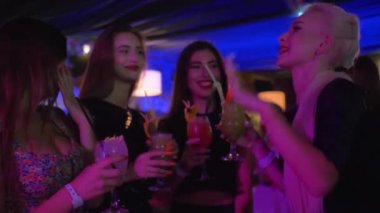 gece kulübünde kutlamak, moda giysiler genç seksi kadın arkadaşlar alkol kokteylleri içme kızlar partide eğlenin