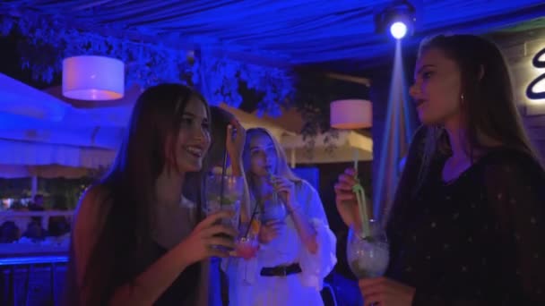Freundinnen im Nachtklub haben Spaß beim Chatten und Trinken von Alkoholcocktails und Tanzen auf der Tanzfläche während eines Junggesellenabschieds
