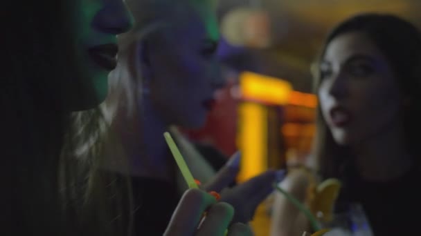 Портрет молодої жінки з красивим макіяжем, що п'є алкогольний коктейль на вечірці зі своїми друзями в нічному клубі — стокове відео