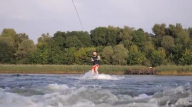 sıçramaları ile motorbot arkasında gemide mutlu wakeboarder sürmek ve halat kolu tutar, hafta sonu boyunca nehir de spor adam eğitim