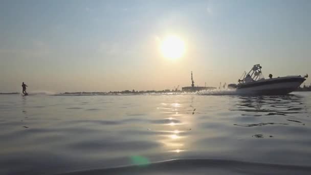 Wakesurf, homem de esportes legal passeios atrás de barco no rio azul com respingos de água durante a noite ensolarada — Vídeo de Stock