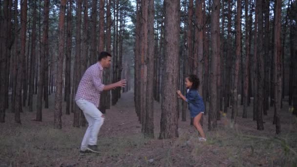 Familia se divierten en el bosque, papá joven jugando en ponerse al día con la hija del niño entre filas de pinos durante las vacaciones en cámara lenta — Vídeos de Stock