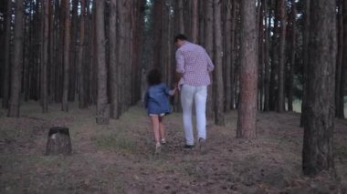 yavaş hareket akşam saatlerinde ormanda çam sıraları arasında çalışan el ele tutuşan kızı ile neşeli baba