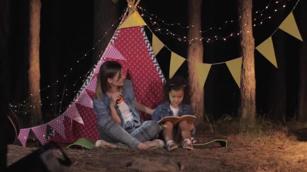 Rapporto genitore-figlio, madre amorevole e belle bambine che si divertono insieme leggendo un libro divertente sul picnic nella foresta nel fine settimana all'aperto — Video Stock