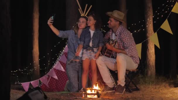 Photo de parents, famille souriante prenant un fond selfie d'un wigwam par le feu en vacances dans la forêt — Video