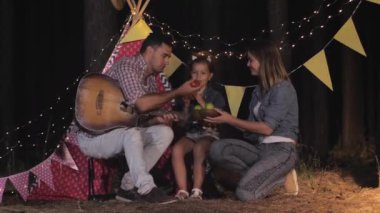 Piknikteki akrabalar, anne ve baba ve bebek geceleri ormanda Wigwam 'a karşı dinleniyorlar.