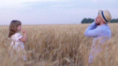 Dost canlısı aile, mutlu akrabalar baba ve küçük kız hasat zamanı buğday tarlasında iyi eğlenceler.