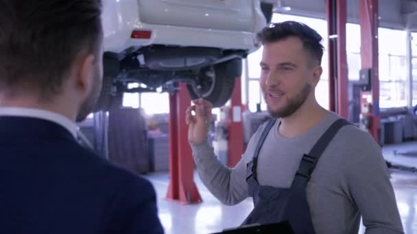 Mecánico acertado del reparto y dueño del coche, hombres que dan la mano en el fondo del automóvil en el ascensor — Vídeos de Stock