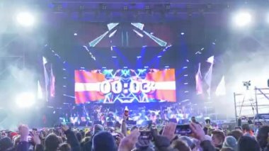 uçan renkli serpantin arka planda elinde cep telefonları ile insanların duygusal bir kalabalık izlerken sahnede konserin başlangıcına dijital geri sayım