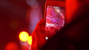 elinde cep telefonu konser de akşam spot ışıkları ve insanların kalabalık bir sahne vuruyor