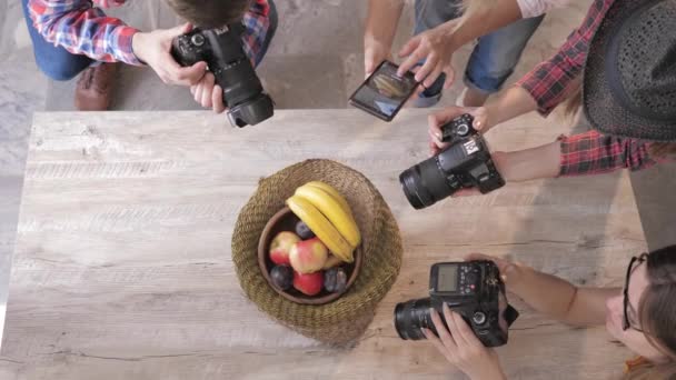 Cameramans λήψη φωτογραφιών στην ψηφιακή φωτογραφική μηχανή και σε ένα κινητό τηλέφωνο φρούτα σε ένα καλάθι στο ξύλινο τραπέζι κατά τη διάρκεια ενός Master Class, κοντινό — Αρχείο Βίντεο