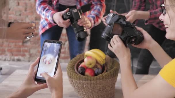 Opérateurs modernes utilisent des appareils photo et un téléphone portable pour prendre des photos de fruits dans le panier sur une table en bois pendant la classe de maître — Video