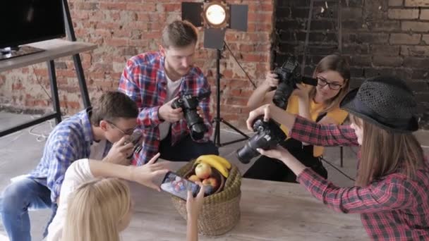 Classe master foto, i giovani fotografi imparano a scattare foto di frutta in cesto con l'uso di fotocamere e telefono cellulare con attrezzature in uno studio — Video Stock