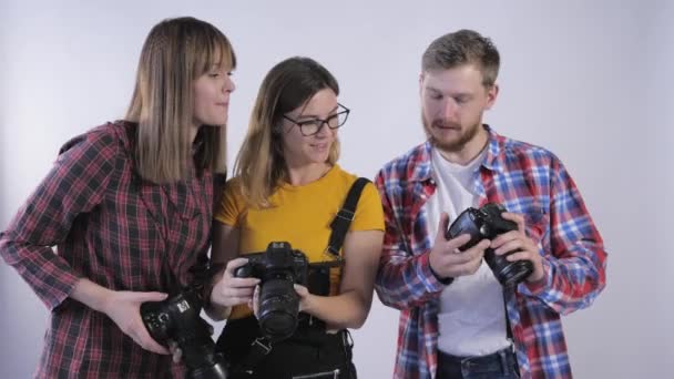 Compañía de profesionales con cámaras digitales en sus manos estudiando fotografías tomadas en estudio fotográfico durante el seminario para fotógrafos — Vídeo de stock