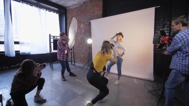 Motefoto, vakre unge positurer for fotograf i studio, han tar bilder med profesjonelt kamera og assistenter – stockvideo
