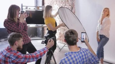 Sahne arkası fotoğrafçıları, profesyonel kameramanlar fotoğraf stüdyosundaki güzel modelin fotoğrafını çeker.