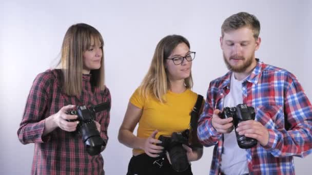 Escola de fotografia, empresa de jovens cinegrafistas com câmeras digitais em suas mãos discutindo fotos em estúdio — Vídeo de Stock