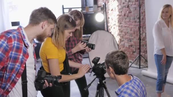 Taller de fotógrafos, en estudio fotográfico profesional se está formando a jóvenes camarógrafos con cámaras digitales sobre fondo de lámparas de iluminación — Vídeos de Stock