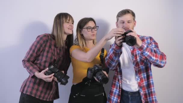 Jovens profissionais com câmeras digitais nas mãos discutem fotos feitas durante um seminário para fotógrafos em um estúdio de fotografia — Vídeo de Stock