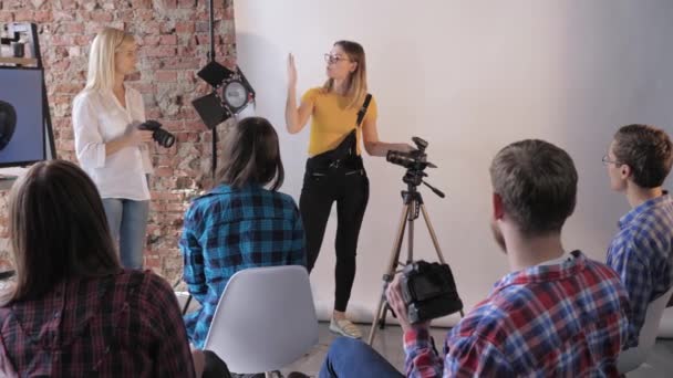 Εργαστήριο φωτογραφίας, ομάδα νέων με ψηφιακές φωτογραφικές μηχανές στα χέρια μελετά το φακό και τη συσκευή λήψης σε επαγγελματικό φωτογραφικό στούντιο — Αρχείο Βίντεο