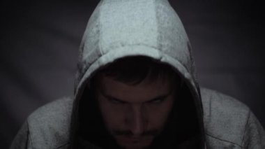 Karanlık arka planda sessiz bir adam hayattaki sorunlar ve depresyon konsepti yüzünden çaresizce kameraya bakıyor.