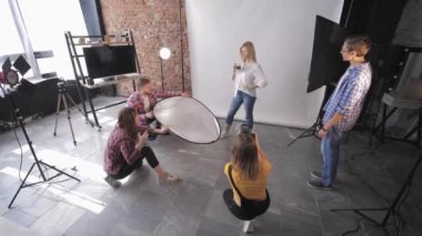 Bir grup fotoğrafçı ve asistanları profesyonel bir stüdyoda güzel bir mankenle fotoğraf çekiyorlar.