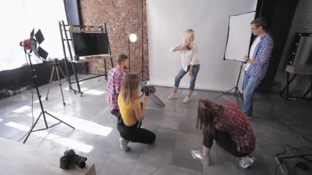 Fotógrafos de moda llevan a cabo sesión de fotos con el modelo en el estudio durante el seminario para fotógrafos en el fondo de lámparas de iluminación — Vídeos de Stock