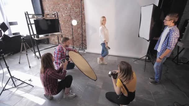 Motesesjon, gruppe av unge kreative mennesker lærer seg studioopptak under fotovirksomheten på bakgrunn av belysningslamper – stockvideo