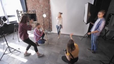 Bir fotoğraf stüdyosunda, asistanları olan bir grup genç profesyonel fotoğrafçı güzel bir kızla fotoğraf çekimi yapıyor.