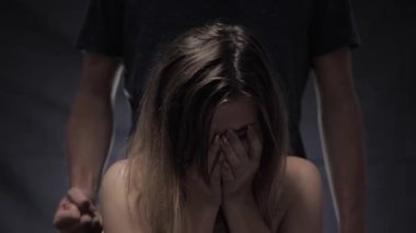 saldırganlık ve aile içi şiddet, ağlayan kız bir yumruk ile arkasında duran kocasının arka plan karşı elleri ile yüzünü örttü