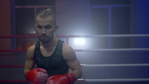 Боевые искусства, боксер парень в боксёрских перчатках выполняет удары на ринге во время тренировки перед соревнованиями крупным планом на спортивной студии — стоковое видео