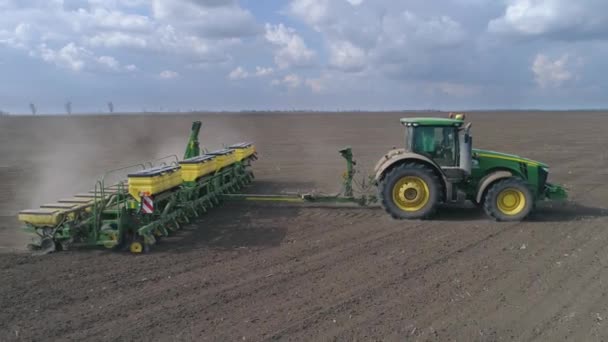 Agricultural industry, tractor during plowing rides across large brown field with plows on background of blue sky — Stock Video