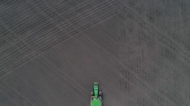 Vista del dron del tractor verde moderno con arados trabaja la tierra en el campo en primavera — Vídeos de Stock