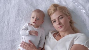 aile ve mutluluk, sevgi dolu genç anne kucaklar ve beyaz arka planda yatan yeni doğmuş bir kızı öper ve kameraya bakmak