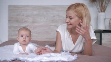 mutlu aile, yeni doğan kızı ile yeni genç anne yatakta yatan ve kamera bakmak