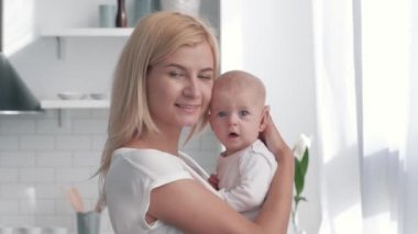 anne elinde yeni doğan bebek, mutlu ebeveyn küçük kız kucaklar ve mutfakta kameraya bakmak