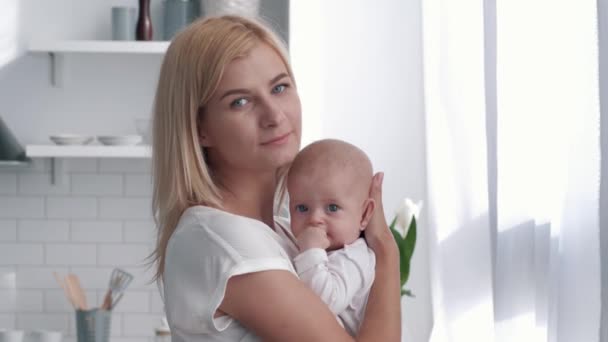 Nouvelle mère câlins et bisous bébé fille sur la cuisine, portrait de famille heureuse à la maison — Video