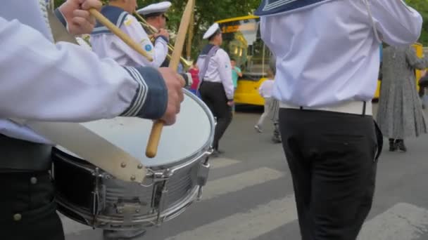 Bubeník v pochodové kapele, mladý námořník s holí v rukou close-up hraje na velký buben během průvodu na ulici — Stock video