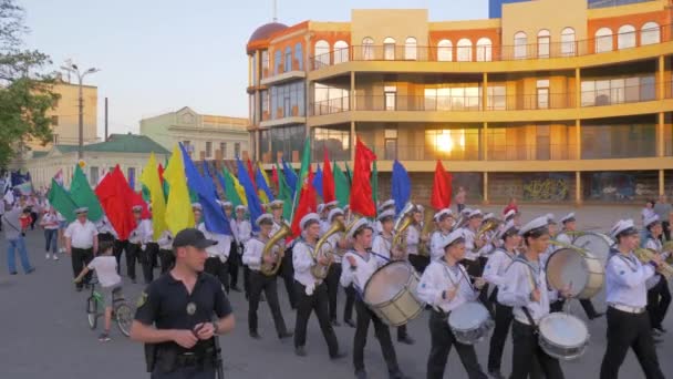 Şehrin ana caddesinde yürüyen denizciler orkestrası, geçit töreninde renkli bayraklarla Deniz Akademisi öğrencileri — Stok video