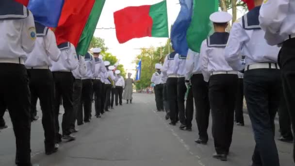Marynarze ubrani w mundur iść z kolorowymi flagami i instrumentami muzycznymi na ulicy na paradzie — Wideo stockowe