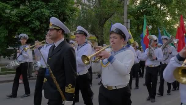Моряки играют на музыкальных инструментах и носят цветные флаги на улице во время парада — стоковое видео