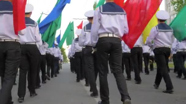 Jovens marinheiros de uniforme branco em desfile marchando com bandeiras multicoloridas na rua — Vídeo de Stock